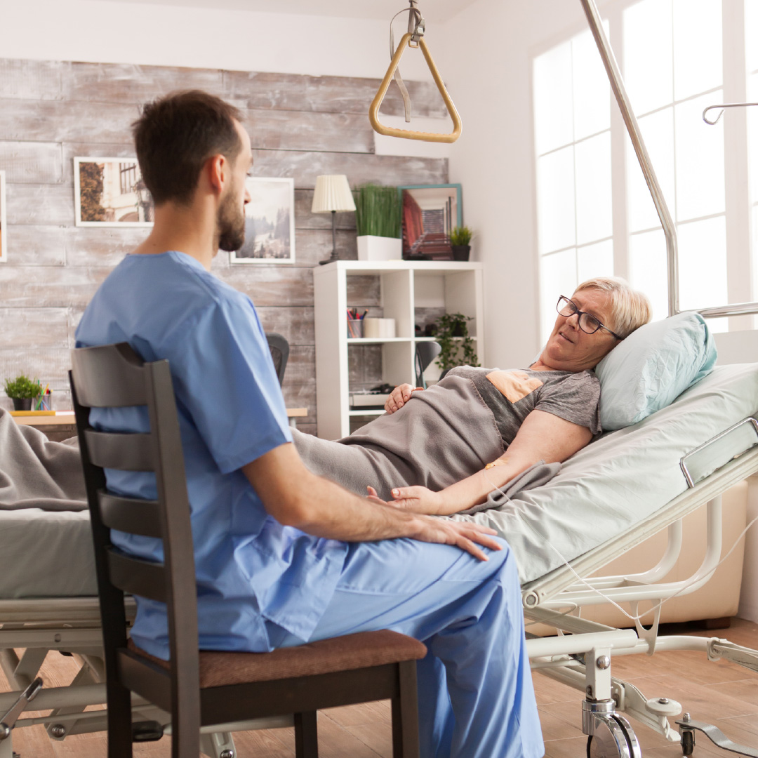 Cuidador acompañando a un paciente en su cama durante una internación domiciliaria